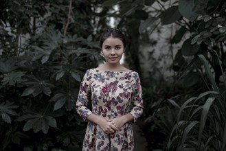 Asian woman smiling near foliage