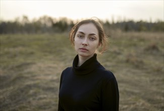 Serious Caucasian woman standing in field