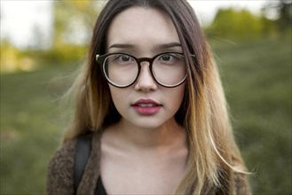 Asian teenage girl wearing eyeglasses in field