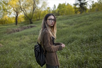 Asian teenage girl carrying backpack in field