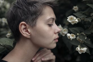 Profile of Caucasian woman smelling flowers