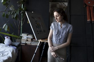 Pensive Caucasian artist holding paintbrushes
