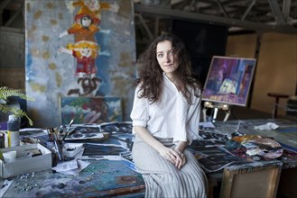 Caucasian artist sitting on table in studio