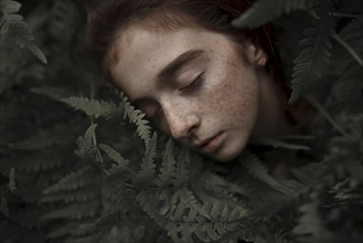 Caucasian girl with freckles resting in leaves