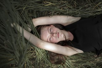 Serious Caucasian woman laying in tall grass
