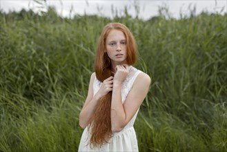Portrait of serious Caucasian girl with freckles standing in field