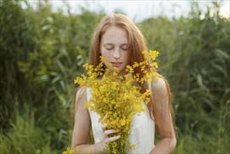 Caucasian girl smelling wildflowers