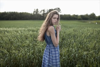 Wind blowing hair of serious Caucasian woman in field