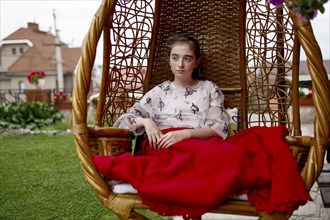 Caucasian girl sitting in hanging chair outdoors