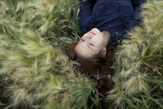 Pensive Caucasian girl laying in field