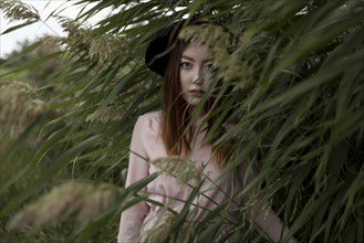 Portrait of serious Asian woman standing in field of tall grass