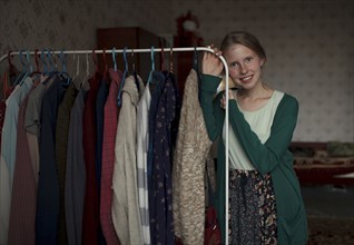 Portrait of pensive Caucasian woman leaning on clothing rack