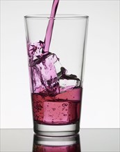 Pink liquid filling glass with ice