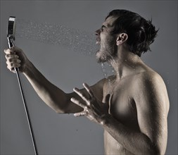 Caucasian man spraying himself in the face with shower