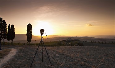 Camera in field on tripod at sunset