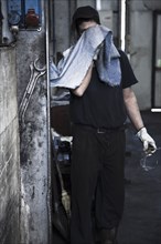 Caucasian worker wiping his face in factory