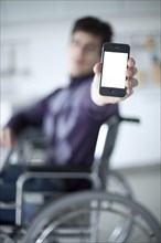 Caucasian man in wheelchair holding cell phone
