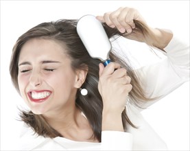 Grimacing woman brushing tangles from hair