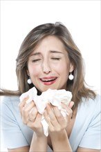 Woman sneezing into tissues