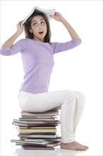 Woman sitting on stack of books