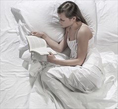 Hispanic woman reading in bed