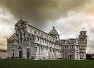 Ornate cathedral and leaning tower under cloudy sky