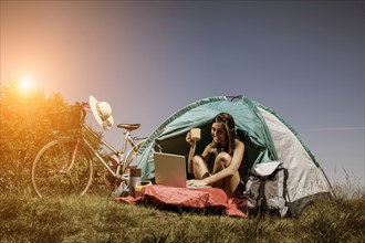 Woman using laptop in camping tent
