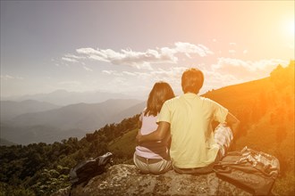 Couple sitting on rock admiring scenic view of mountain