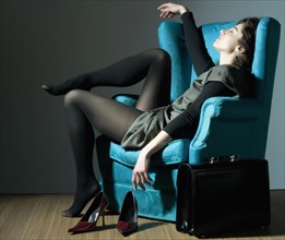 Fatigued Caucasian businesswoman unwinding in blue armchair