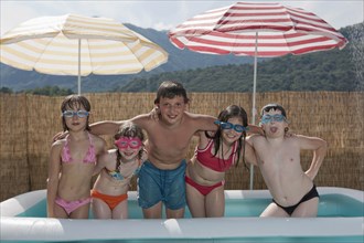 Smiling Caucasian children posing in inflatable swimming pool