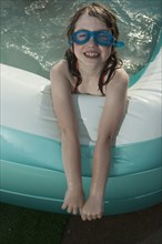 Smiling Caucasian girl in inflatable swimming pool