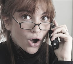 Surprised Caucasian businesswoman talking on telephone