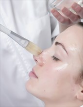 Caucasian woman receiving facial beauty treatment