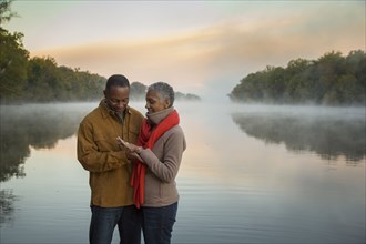 Older couple looking at ring at foggy river at sunrise