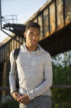 Mixed Race man with backpack leaning on urban railing