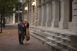 Older romantic couple walking on city sidewalk