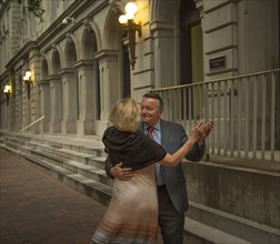 Older romantic couple dancing on city sidewalk