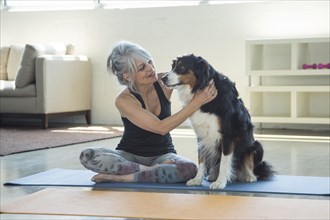 Woman on exercise mat petting dog