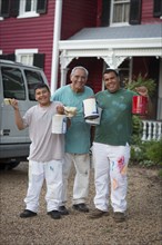 Smiling Hispanic men and boy posing with paint cans and paintbrushes