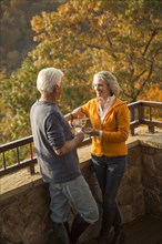 Older Caucasian couple enjoying wine and scenic view