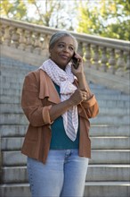 Black woman on stone staircase talking on cell phone