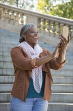 Black woman posing for cell phone selfie on stone staircase