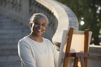 Black woman painting on canvas near stone staircase