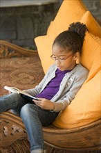 Mixed Race girl sitting on sofa reading book
