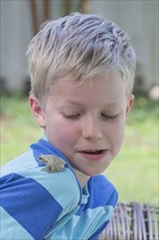 Close up of Caucasian boy looking at frog on shoulder