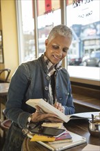 Mixed Race woman reading travel guidebook in coffee shop