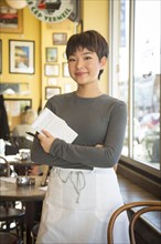 Portrait of Asian teenage waiter posing in coffee shop