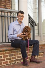 Portrait of Caucasian man holding dog and texting on cell phone