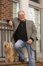Portrait of Caucasian man leaning on stoop posing with dog