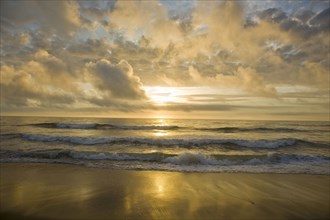 Ocean waves on beach at sunset